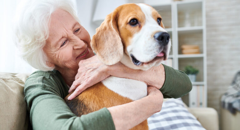 Ältere Frau umarmt einen großen Hund